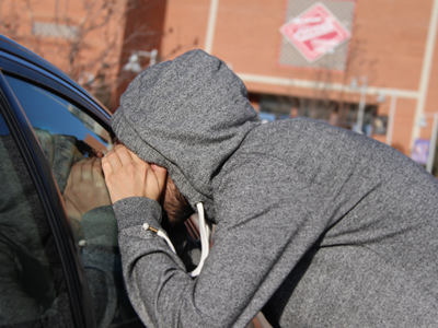 Man peering into a car window in front of the Tivoli Student Union